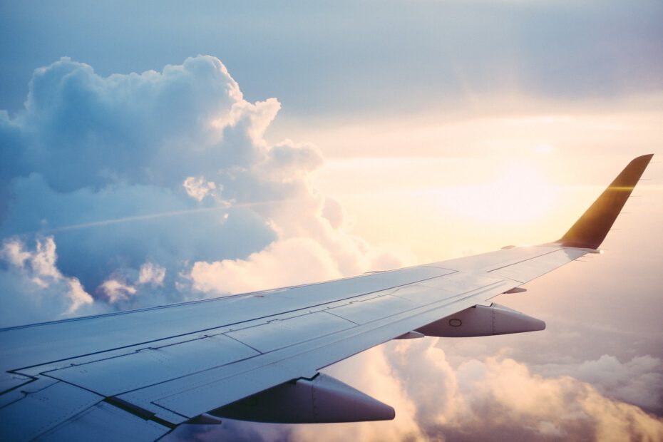 das Foto zeigt den Blick aus einem Flugzeug auf die Wolken und den Sonnenaufgang