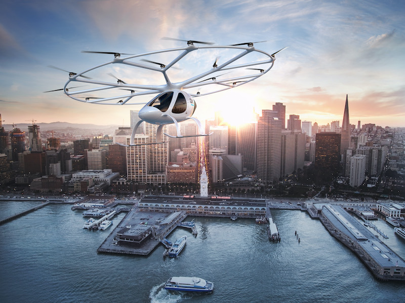das Bild zeigt die Simulation eines Flugtaxis von Volocopter über dem Hafen einer großen Stadt