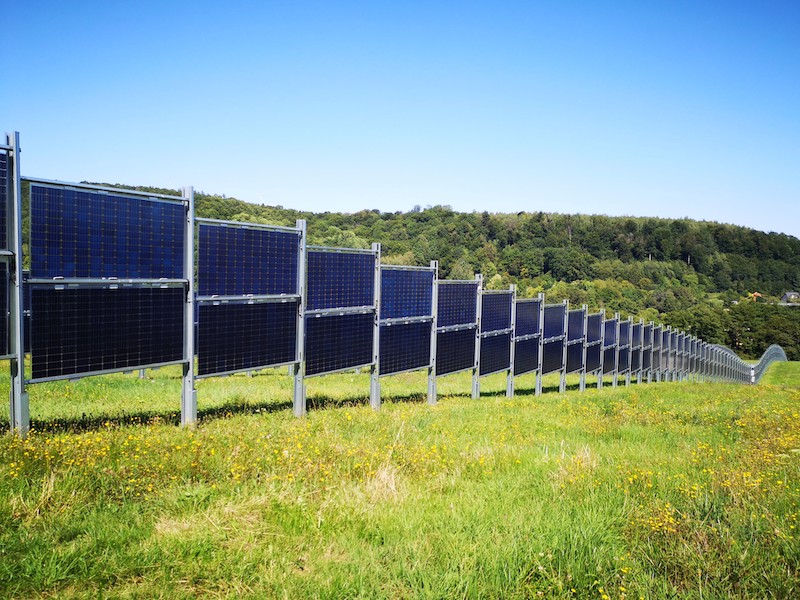 das Photo zeigt eine bifaciale Photovoltaikanlage im Sommer wie sie auch an einem Flughafen zum Einsatz kommen könnte.